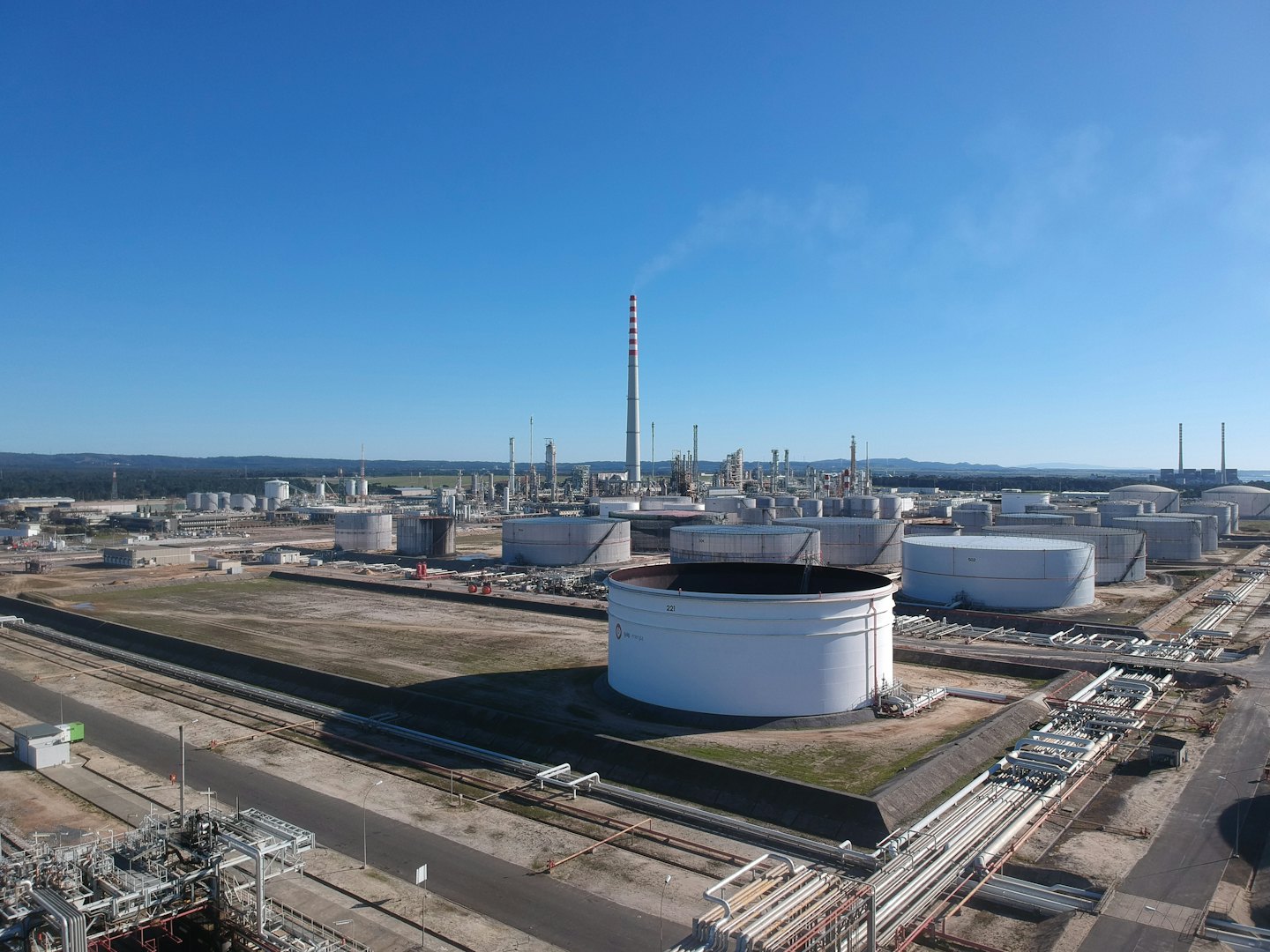 Aerial view of an industrial oil refinery with storage tanks and pipes.
